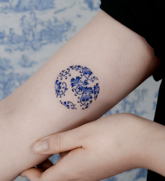 Tatuaje pequeño estilo japonés de tinta azul de círculo con diseño floral en el brazo