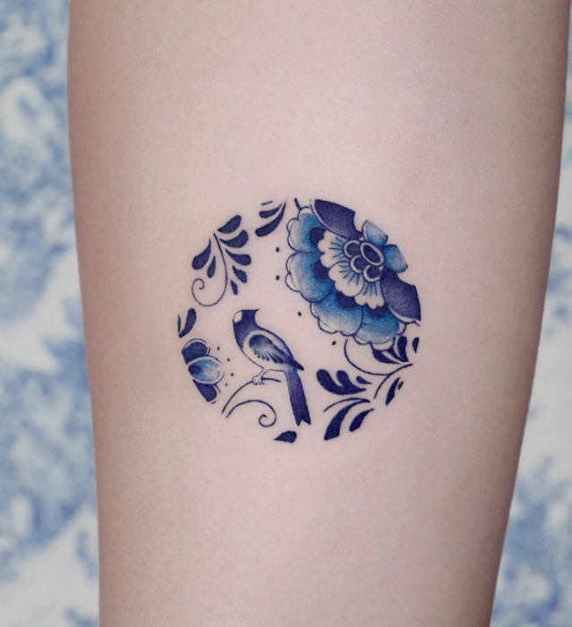Tatuaje pequeño estilo japonés de tinta azul de círculo con diseño floral en el brazo