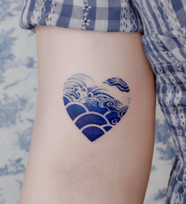 Tatuaje pequeño estilo japonés de tinta azul de corazón con olas de mar en el brazo