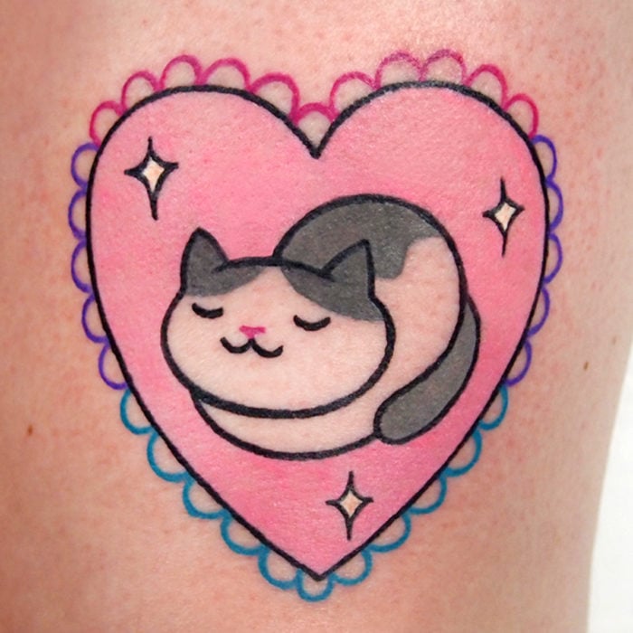 Tatuaje tierno kawaii de gato dormido en un corazón rosa