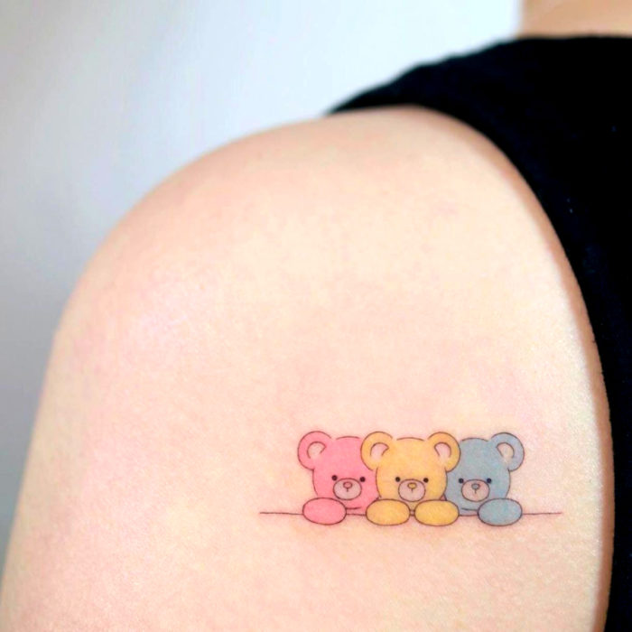 Tatuaje tierno kawaii en el hombro, osos de peluche de colores rosa, amarillo y azul