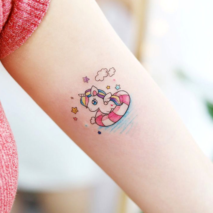 Tatuaje en el brazo, tierno kawaii unicornio bonito en un flotador rosa con blanco