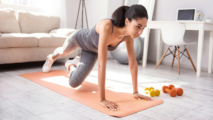 Chica morena haciendo ejercicio en tapete naranja