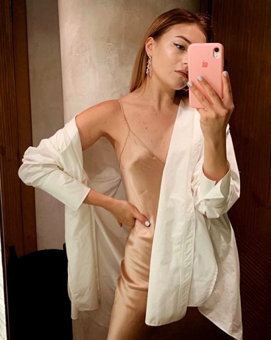 chica rubia usando un vestido de satén slip dress color champaña con camiseta oversized de botones blanca