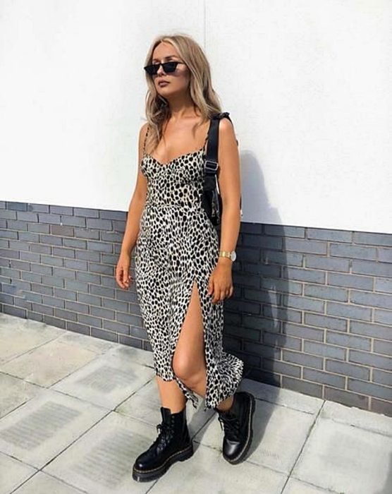 chica rubia usando un vestido de satén slip dress con estampado animal print blanco y negro, botas negras militares, lentes de sol y bolso de mano negro