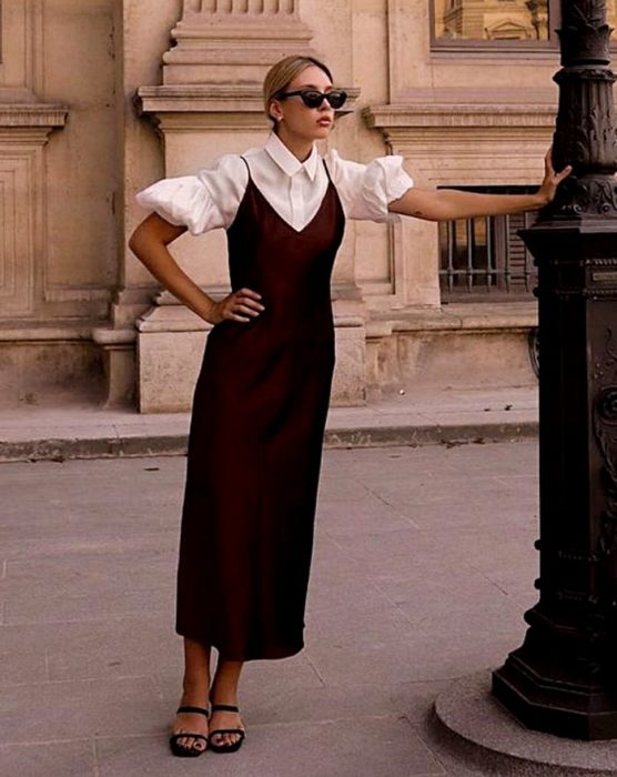 chica rubia con lentes de sol, usando una blusa blancas de mangas de globo con vestido de satén guinda y sandalias de tacón