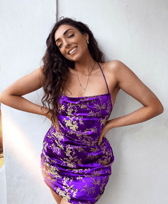 chica morena usando un vestido morado brillante ceñido con tirantes