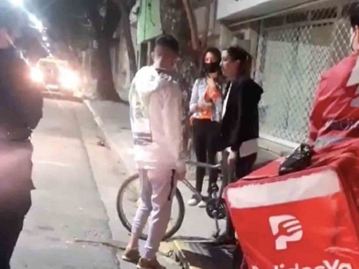 Chica entregándole la bicicleta al joven repartidor a quien le habían robado la suya