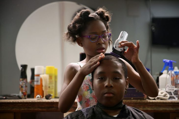 Neijae Graham-Henries cortandole el cabello a un niño