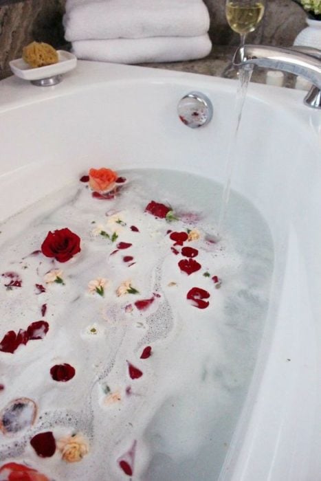 Tina de baño llena y con hojas de rosas