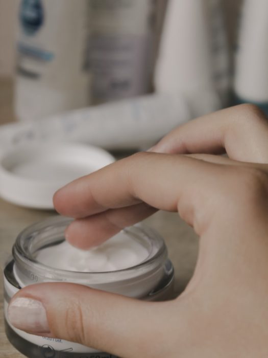 Chica tomando un poco de crema de un tarrito de cristal