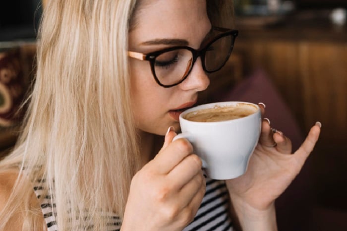 Chica usando lentes y bebiendo una taza de chocolate caliente
