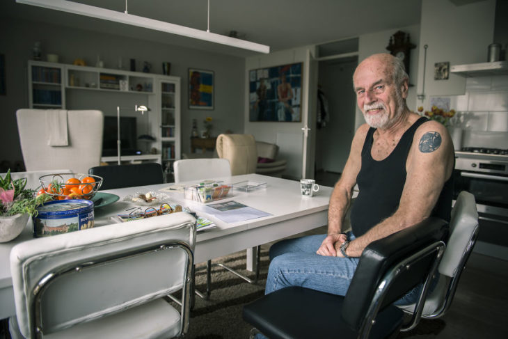 abuelito en su barbería sentado en una silla y mostrando sus tatuajes 