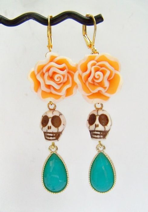 Accesorio inspirado en Día de muertos de aretes de calavera, con una gema en la parte inferior y una flor de sempasuchil en la parte superior