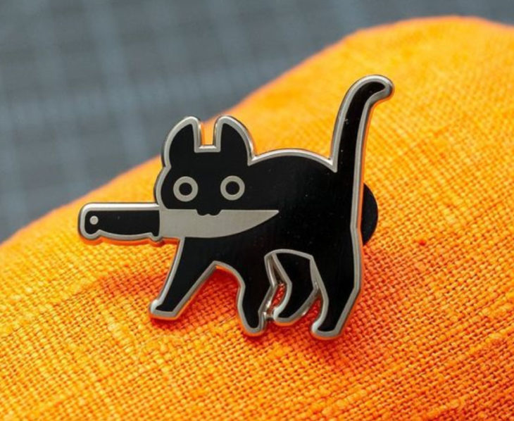 Accesorio inspirado en Halloween de un pin de un gatito negro con un cuchillo