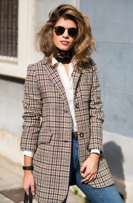 Chica usando jeans, blusa blanca y blazer con estampado tartan en tonos cafés