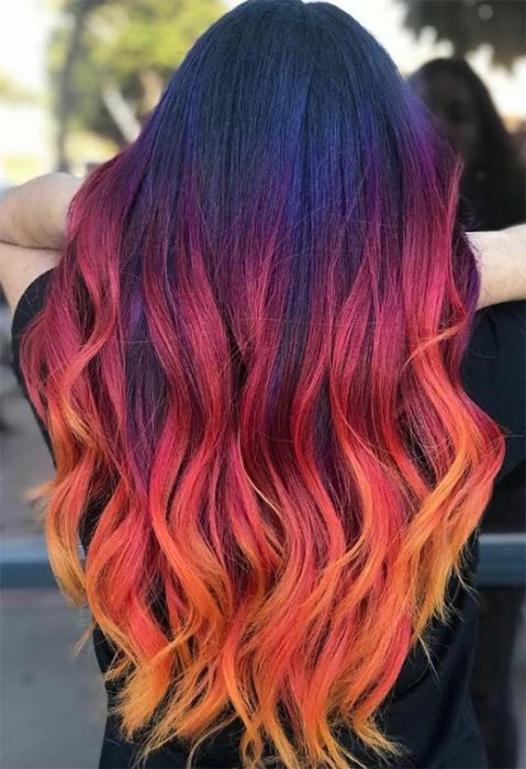 Chica con cabello largo rizado color rojo, amarillo y naranja