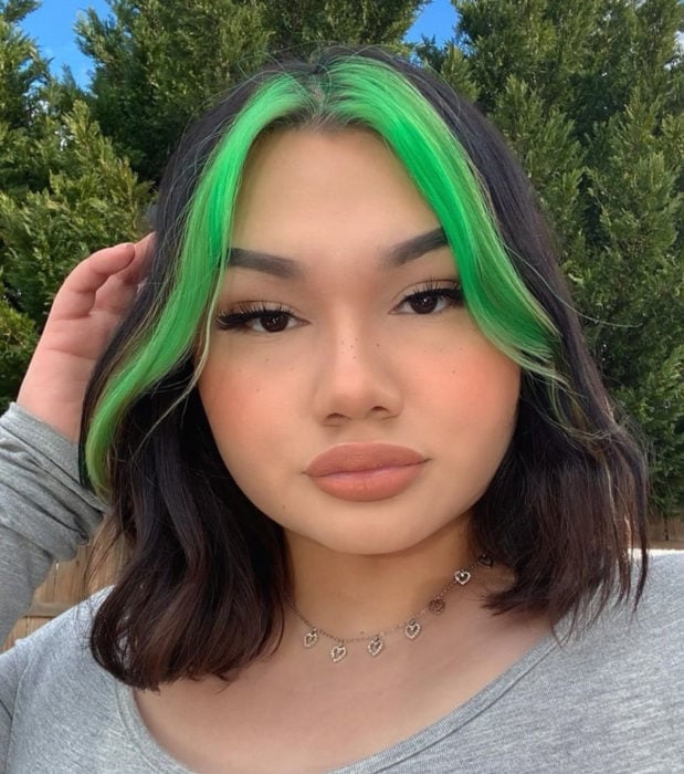 Looks aesthetic con cabello corto color castaño con mechones verde neón, mujer con maquillaje sencillo