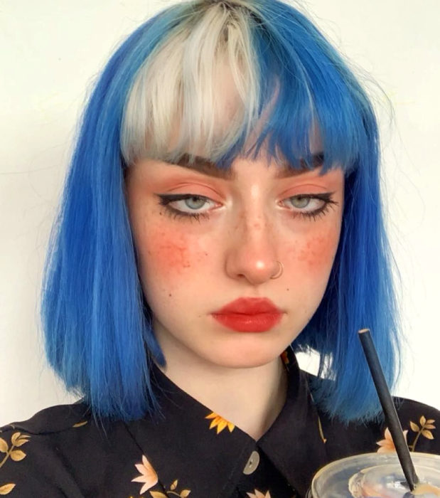 Looks aesthetic con cabello corto color azul y blanco, lacio, con fleco, mujer de ojos verdes, pecas, perforación en la nariz y maquillaje sencillo con mucho blush