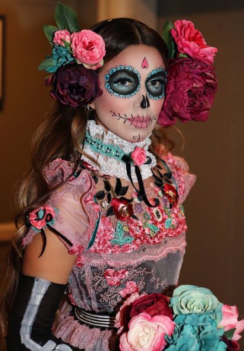 Maquillaje de catrina en rostro completo con tonos aqua y rosas gigantes sobre la cabeza