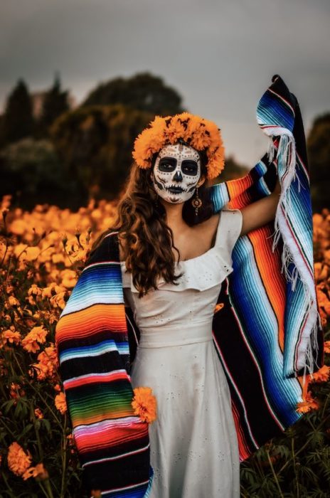 Maquillaje de catrina de rostro completo con detalles negros y corona cempasúchil y cabello suelto