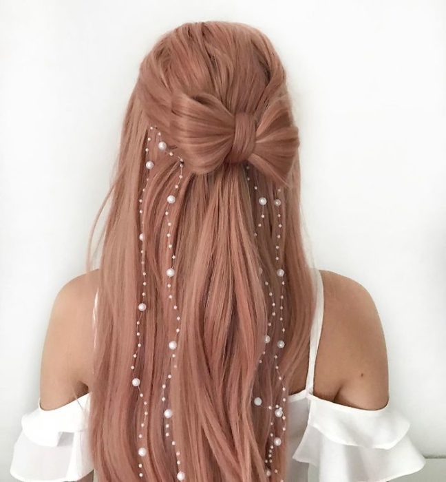 Chica con el cabello trenzado en forma de moño con decoraciones de perlas