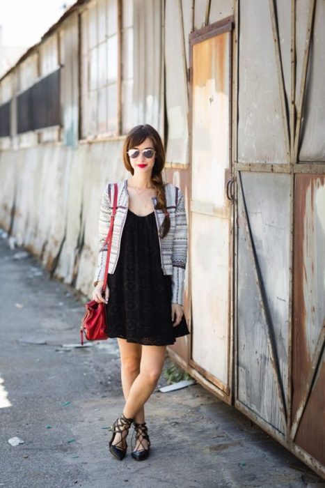 Chica con vestido negro, saco blanco con rayas negras y flats negros con cintas de bailarina