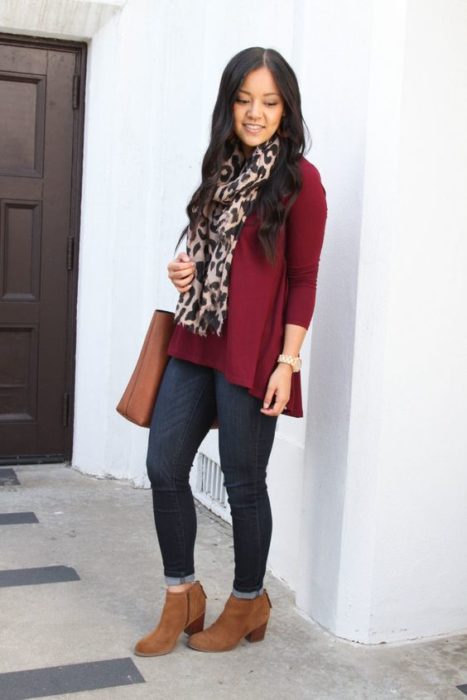 Chica de cabello largo suelto con saco guinda, jeans ocsuros y botines cafés