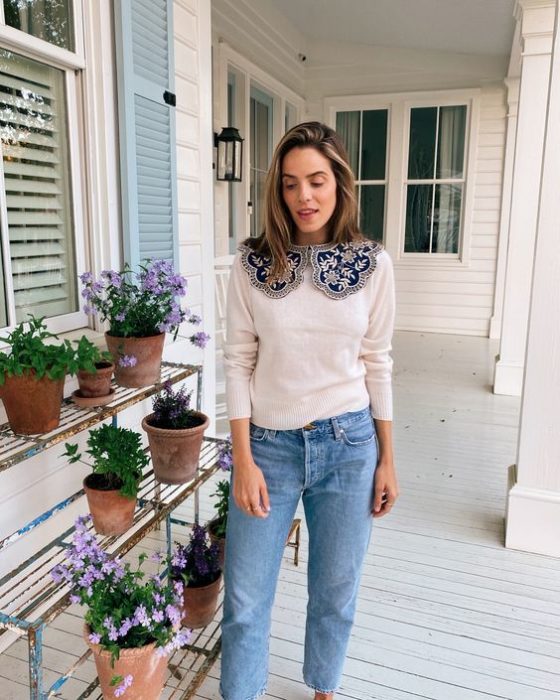 Chica de cabello castaño largo con jeans y suéter blanco con cuello bobo azul