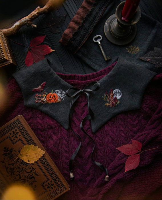 Little pin studio crea bonitos cuellos bordados de Halloween para vestidos y blusas; diseño de calabaza, murciélago, hongos, telaraña y casa embrujada sobre tela negra y suéter tejido rojo vino