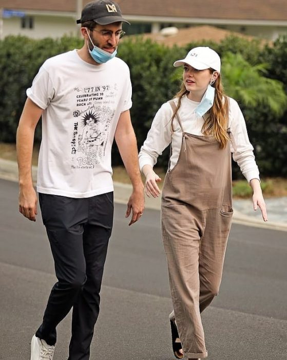 Emma Stone caminando con overol café y gorra blanca