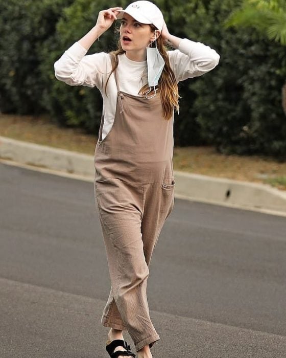 Emma Stone caminando con overol café y gorra blanca