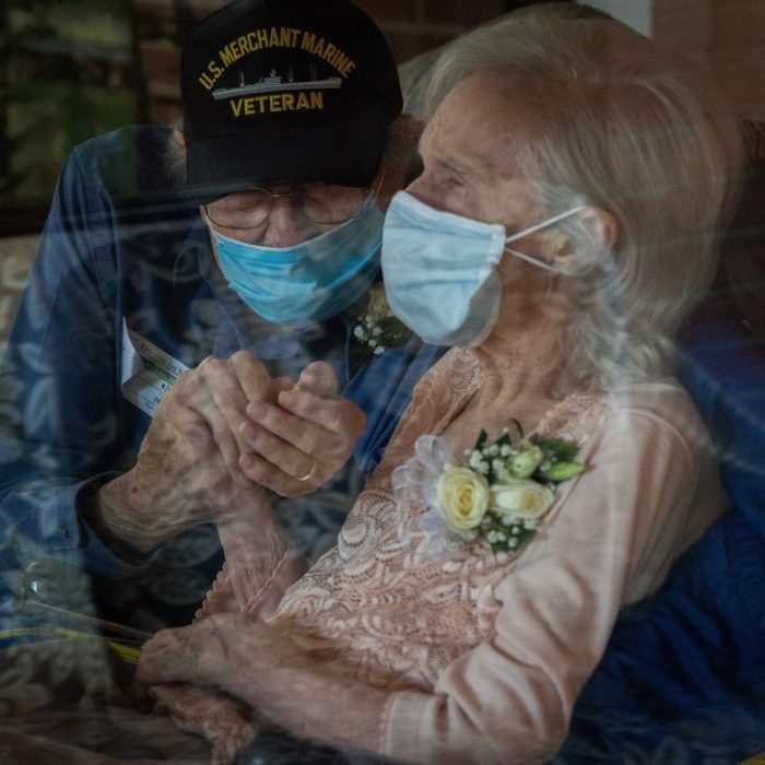 Abuelito sosteniendo la mano de su esposa mientras están juntos dentro de un automóvil 