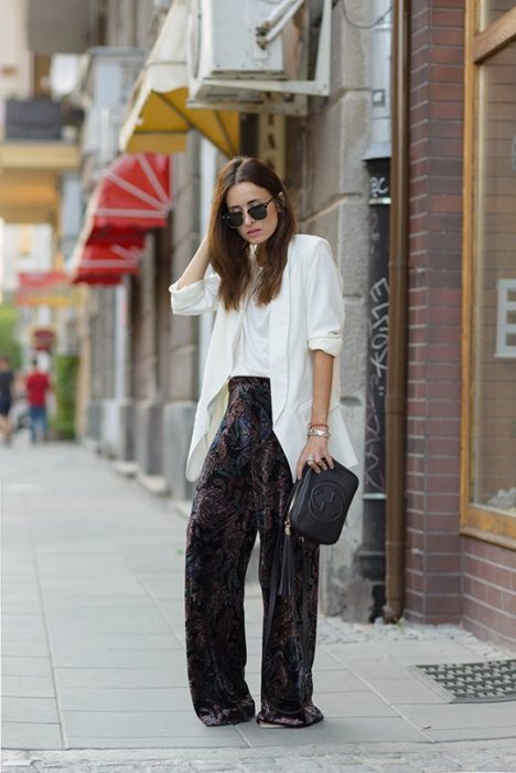 Chica de cabello largo con blusa y saco blancos y pantalón negro de terciopelo