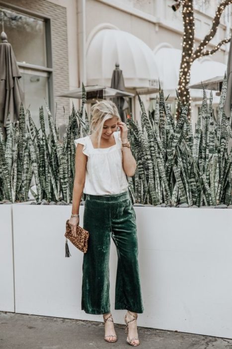 Chica rubia con blusa blanca con pantalón verde esmeralda de terciopelo