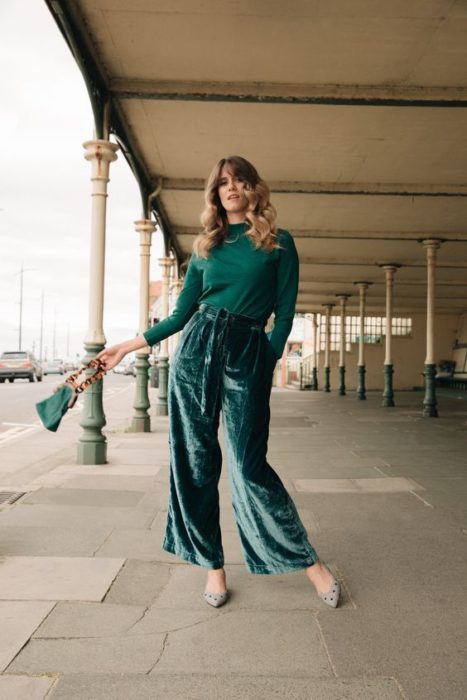 Chica de cabello castaño corto con blusa verde y pantalón verde esmeralda de terciopelo