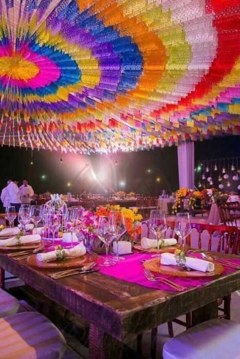 Salón de eventos para boda con decoración mexicana y papel picado en el techo 