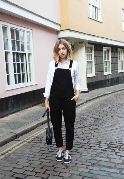 Chica rubia de cabello corto con overol negro con blusa blanca