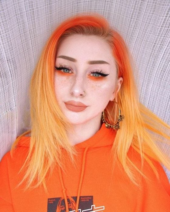 Chica con sombra neón naranja en la parte inferior de los ojos