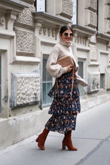 Chica posando con suéter de cuello de tortuga con suéter gris y falsa azul marino con flores y botines color guinda