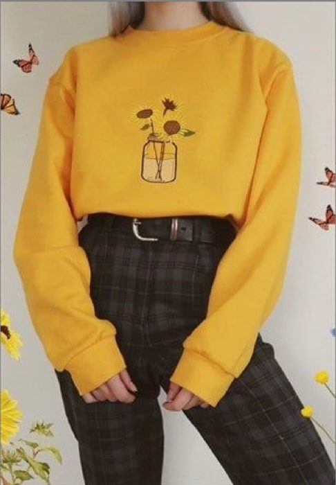 Chica lelvando sudadera amarilla con bordado de girasoles