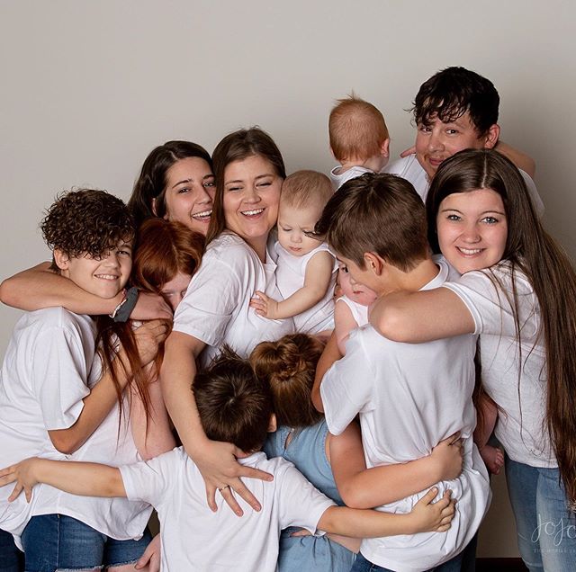 Mujer en una sesión de fotos abrazando a sus 11 hijos 