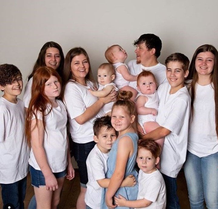 Mujer en una sesión de fotos abrazando a sus 11 hijos 