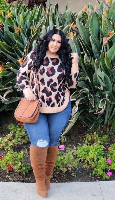 Chica curvy usando botas altas y bolsa camel, jeans de mezclilla y suéter de estampado animal print