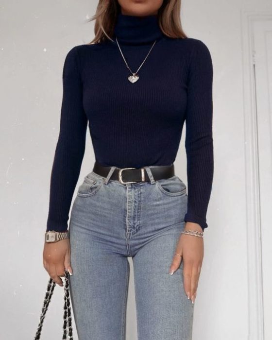 Chica usando jeans de tiro alto denim, con cinturon negro y blusa de manga larga y cuello alto color negro