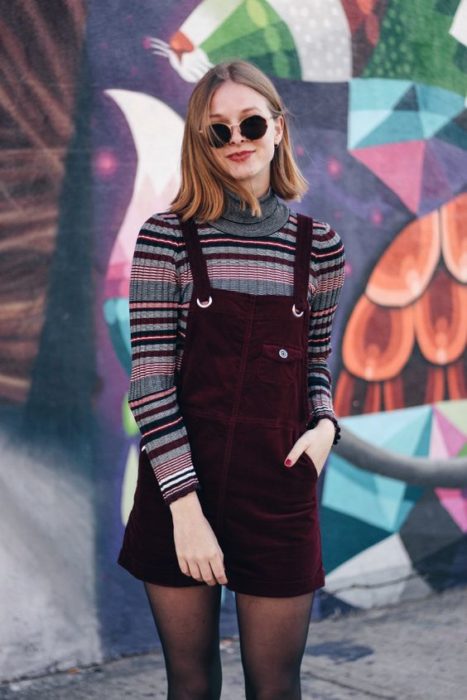 Outfit de pana de vestidito de tirantes con medias negras y blusa de manga larga de estampado rayado y lentes oscuros