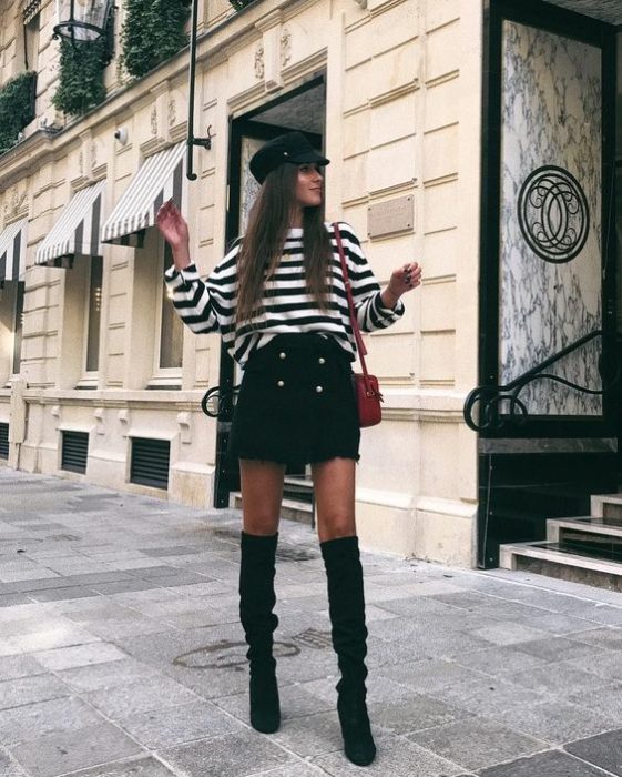 Chica de cabello largo con falda negra y blusa de rayas blanco con negro y gorro