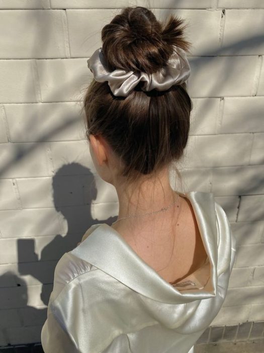 Chica peinada con moño alto con scrunchie color plata