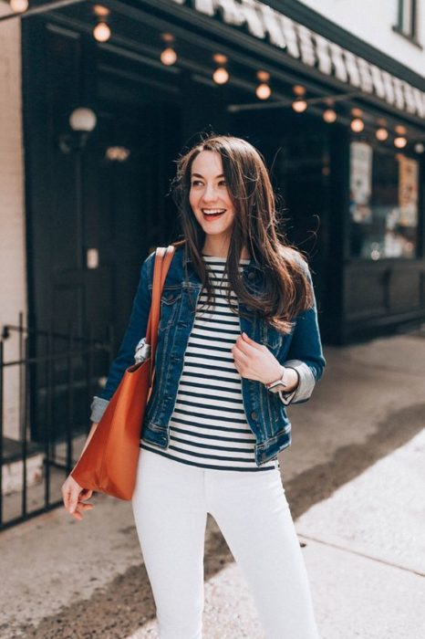 Chica de cabello largo oscuro con blusa de rayas, pantalón blanco y chamarra de mezclilla