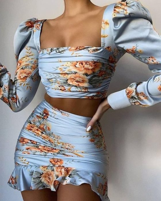 Chica delgada morena con blusa y faldas azules con estampado de flores naranjas